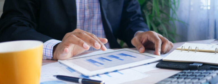 A man looks at bar graphs on his tablet.