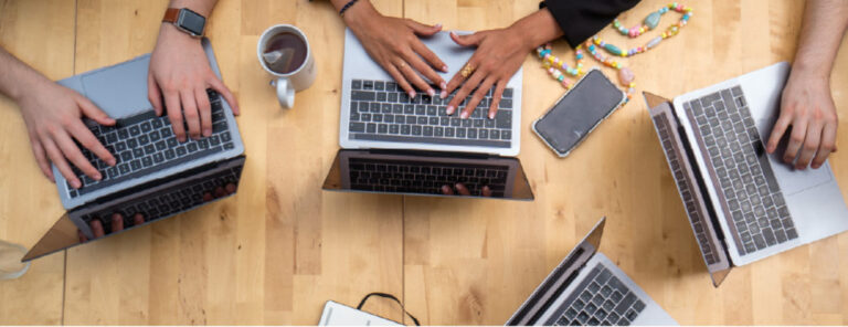 four laptops with various hands typing on them