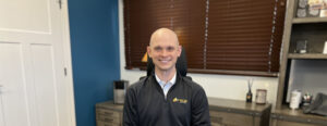 Justin Wilkerson wears an Inline Data Systems quarter zip and sits at his office desk.