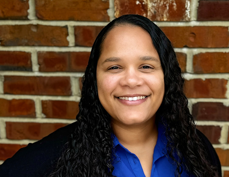 Angel Mozee, Product Manager, smiling in front of a brick wall